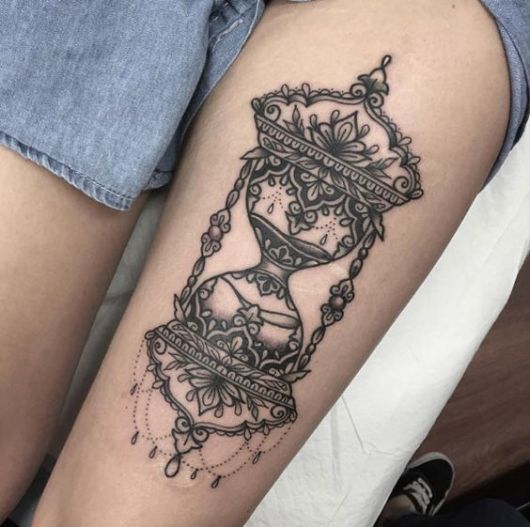 tatuagem feminina de ampulheta na coxa