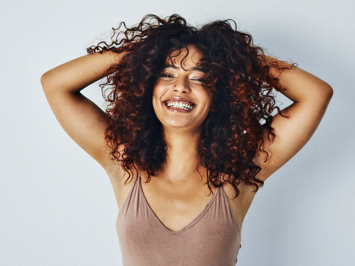 Cortes para cabelo cacheado ideias. Foto mulher negra sorrindo com corte swag nos cabelos