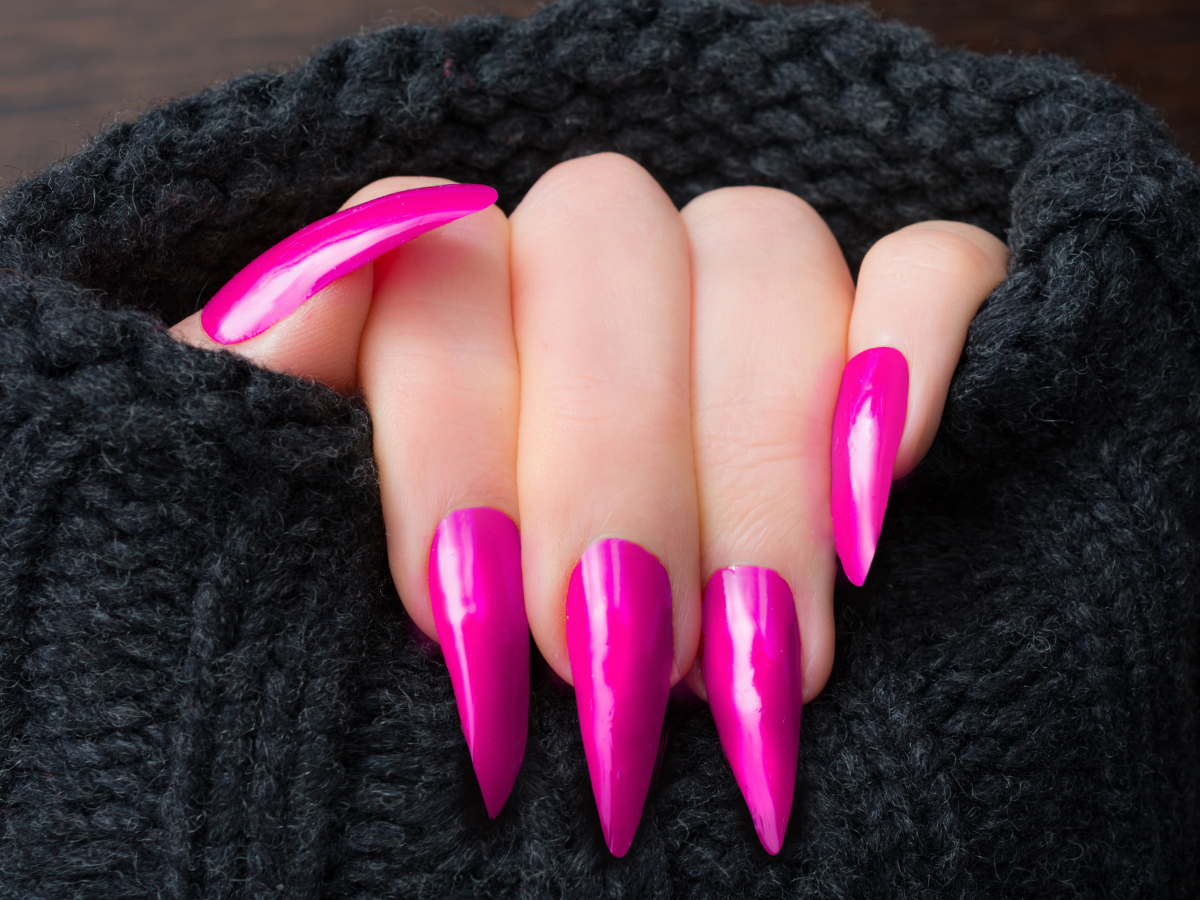 Unhas Stiletto. Foto mão com unhas compridas e pontudas e esmalte rosa