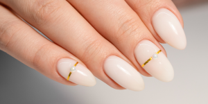 Milk Bath tendências para as unhas. Foto unha com esmalte branco leitoso e detalhes em dourado.