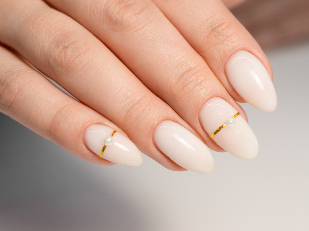 Milk Bath tendências para as unhas. Foto unha com esmalte branco leitoso e detalhes em dourado.