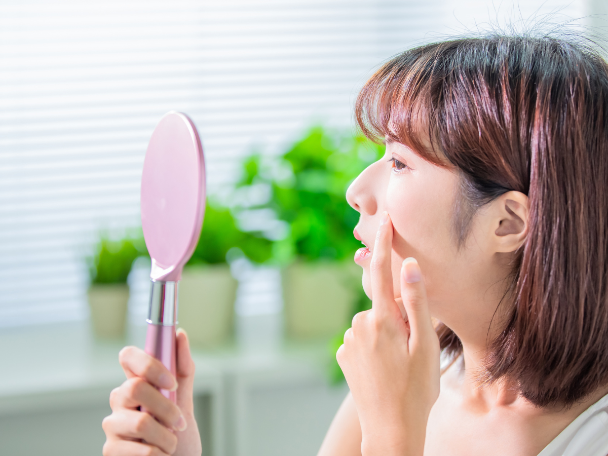 Pele oleosa, produtos essenciais para o skincare. Foto mulher japonesa olhando o espelho e observando a pele.