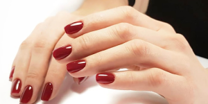 Cores de esmalte românticas para o inverno. Foto mãos com unhas pintadas de vermelho carmim