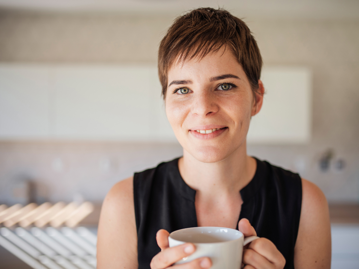 Ideias de cabelos para parecer jovem. Mulher de 40 anos com cabelo pixie e xícara na mão