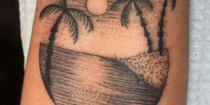 Tatuagens de mar e praia. Foto mostra uma tatuagem com palmeiras, o mar e um pôr do sol ao fundo