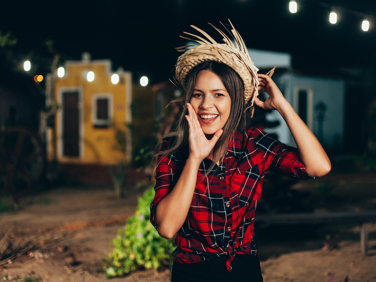 Looks de festa junina. Foto mulher com blusa xadrez vermelha e chapéu de palha