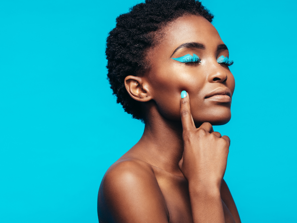 maquiagem para olhos. Foto mostra mulher negra com os olhos fechados e sombra azul. Fundo da foto também é azul.