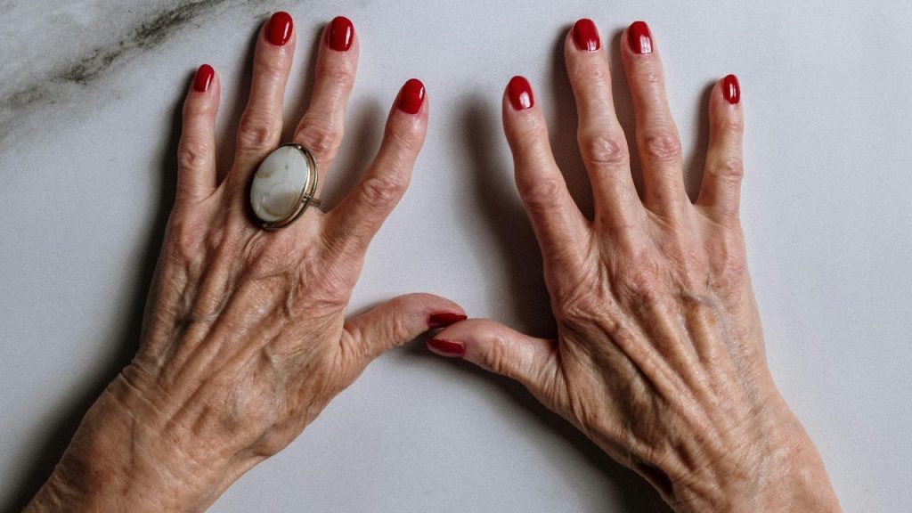 mãos mais velhas com esmalte vermelho