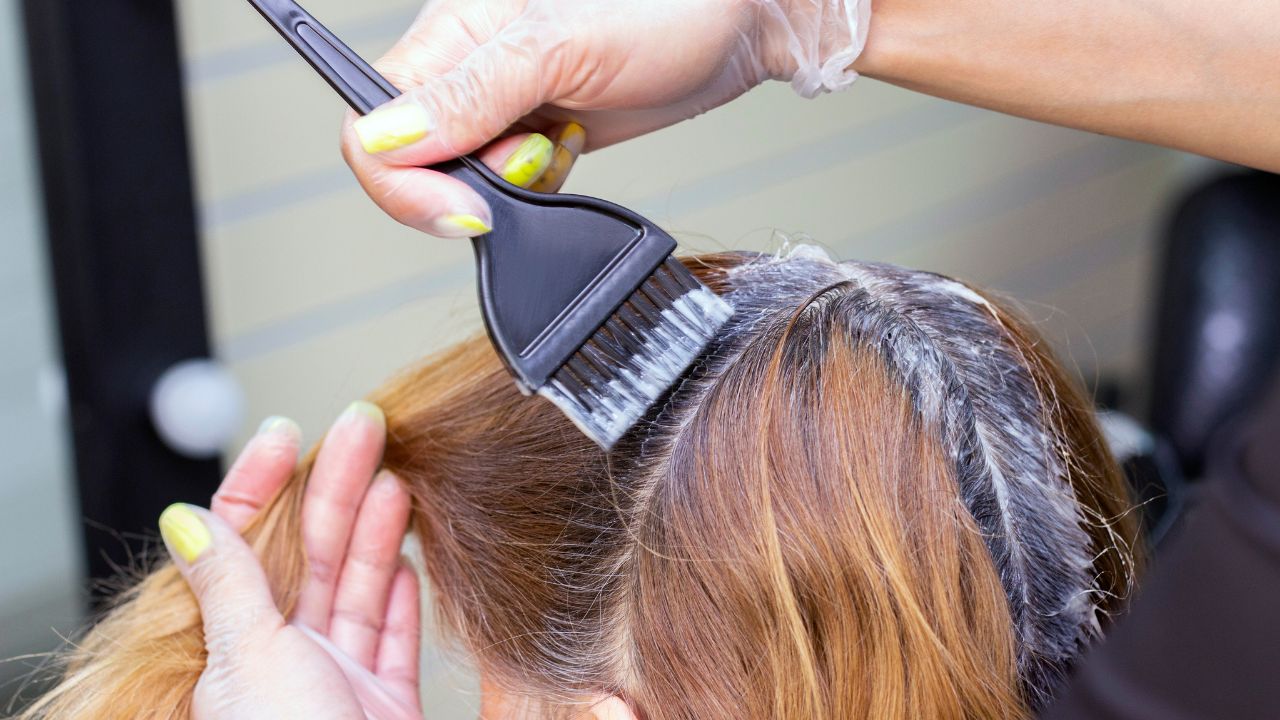 mulher com raiz grisalha pintando cabelo