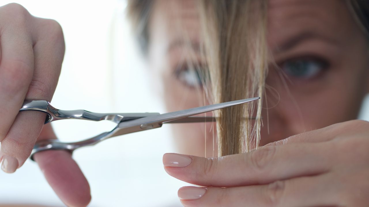 mulher cortando franja de cabelo