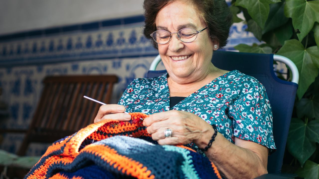 mulher idosa sorrindo e tricotando