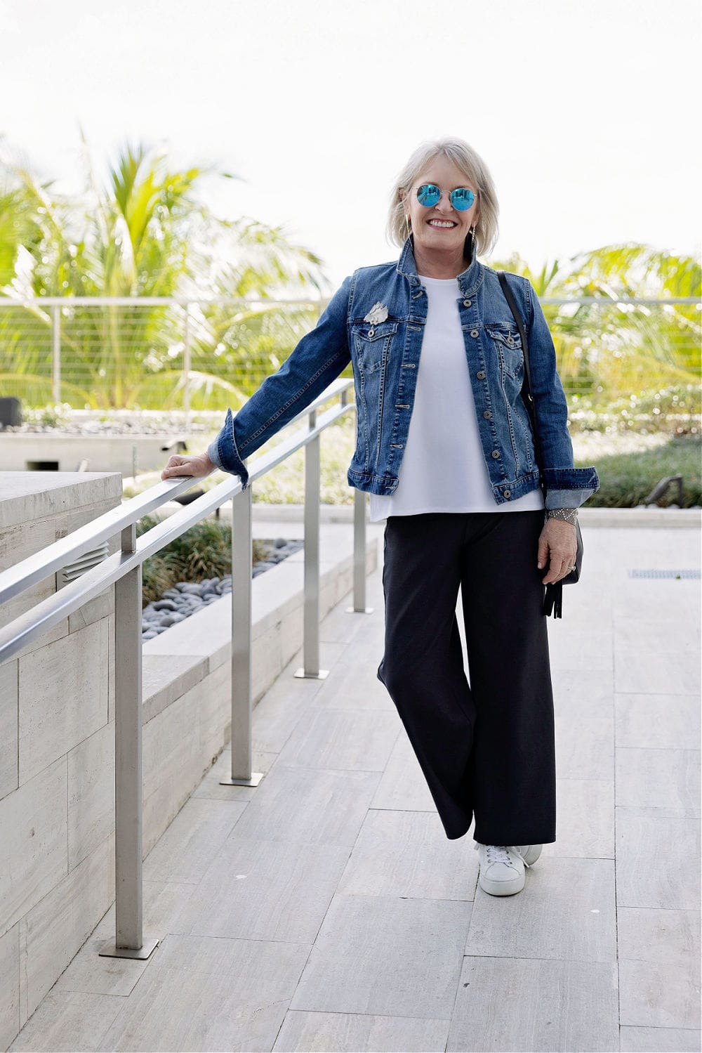 mulher mais velha com jaqueta jeans, blusa branca e calça preta